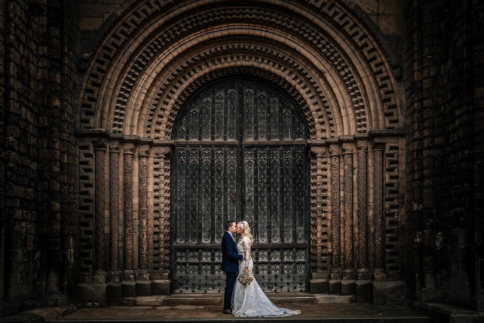 newlyweds kissing in front of lincoln cathedral